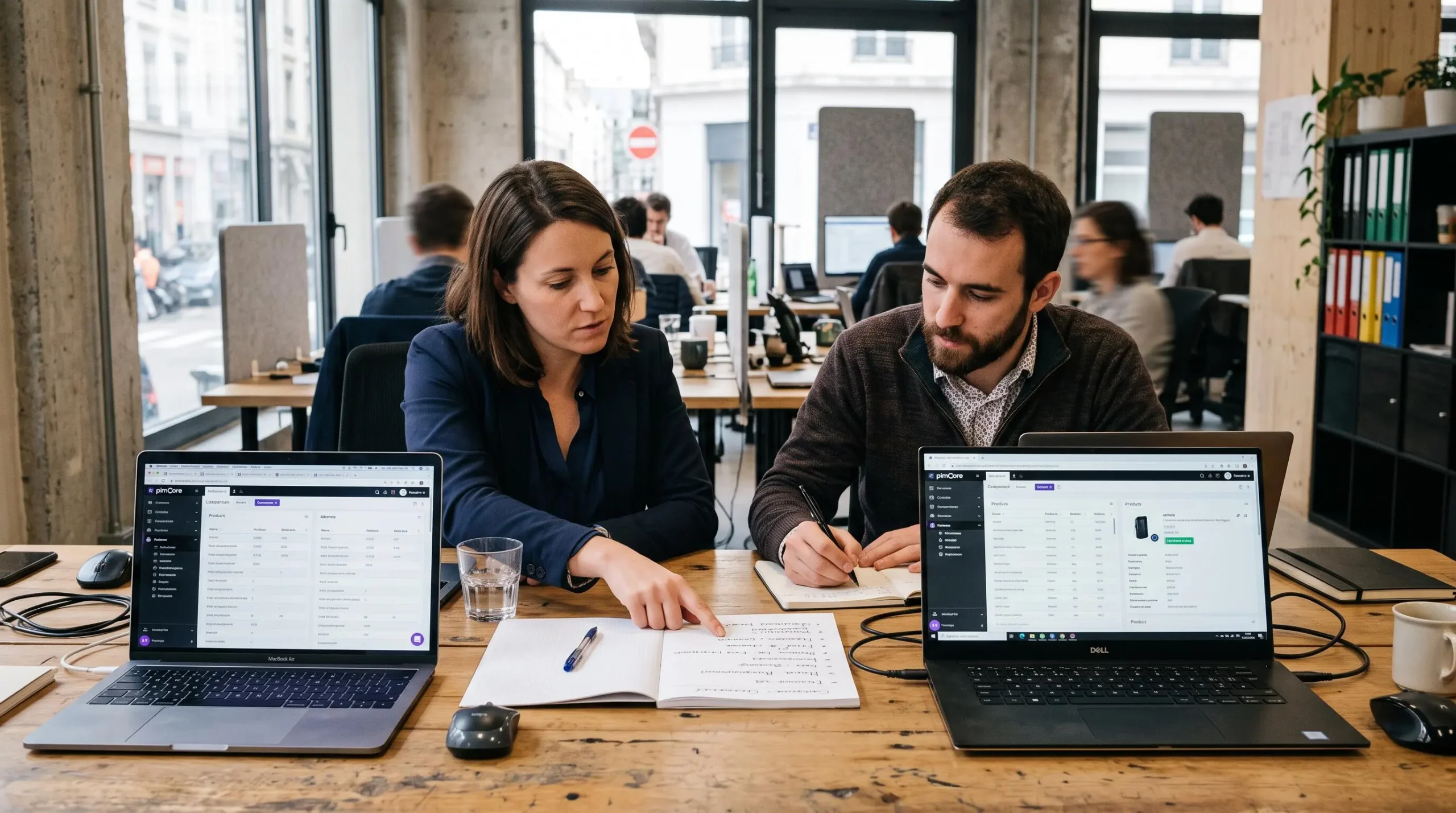 Deux collaborateurs comparent des logiciels PIM sur deux ordinateurs portables au bureau.